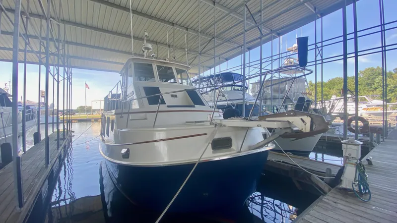 Slide: The Image of 1989 Kadey-Krogen Manatee 36 docked in a covered marina, surrounded by other boats. - 25