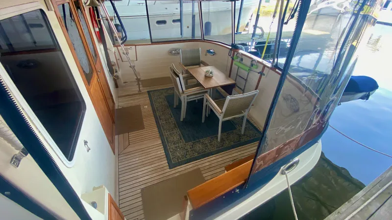 Slide: The Image of 1989 Kadey-Krogen Manatee 36 yacht deck with dining area and wooden flooring. - 27