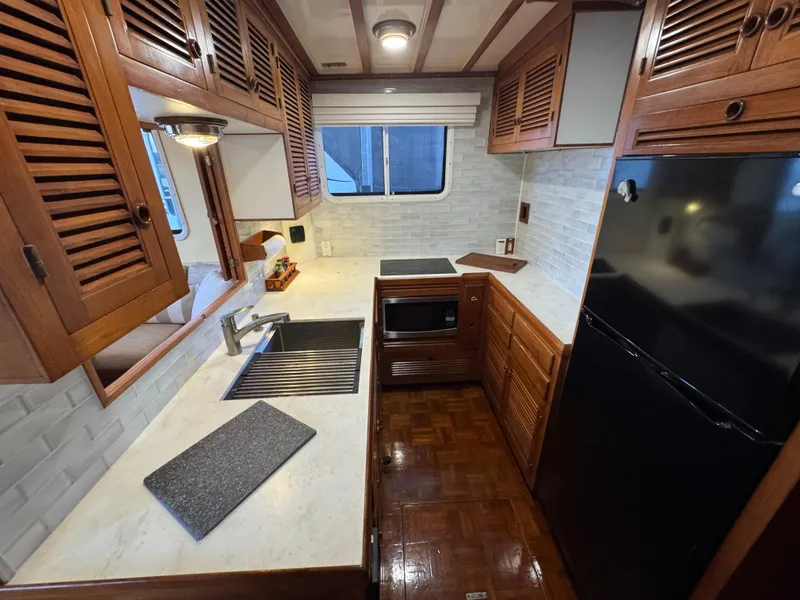 Slide: The Image of 1989 Kadey-Krogen Manatee 36 yacht kitchen with wood cabinets, modern appliances, and white countertops. - 35