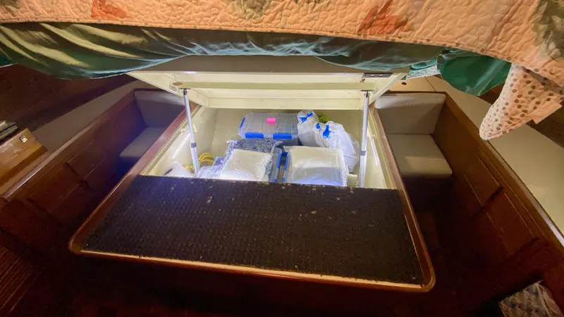 Slide: The Image of Under-bed storage in 1989 Kadey-Krogen Manatee 36, filled with various items. - 46