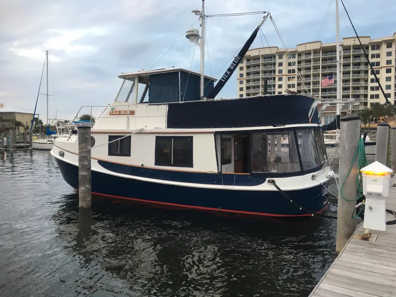 Slide: The Image of 1989 Kadey-Krogen Manatee 36 yacht docked in marina, featuring blue and white exterior. - 6
