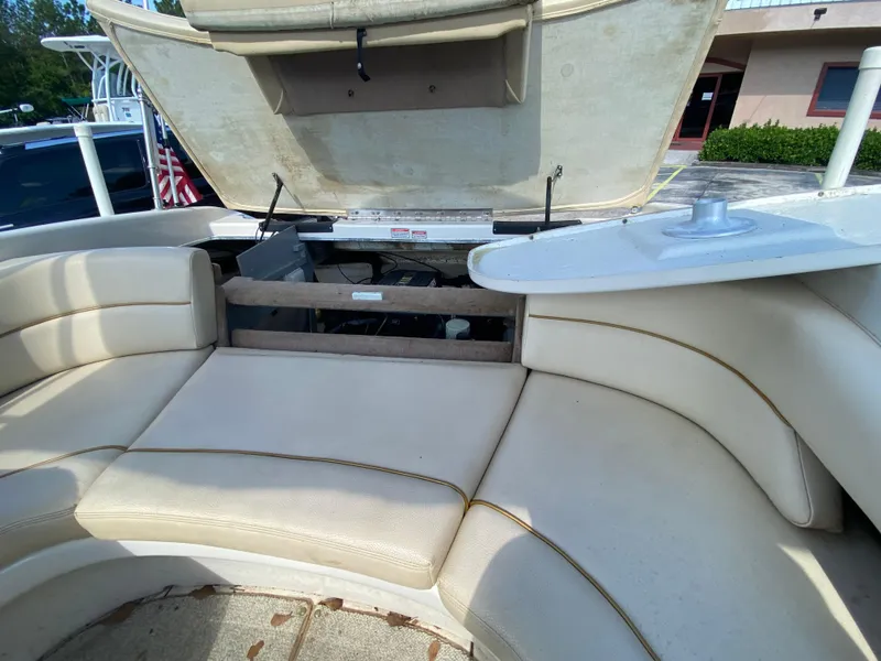Slide: The Image of 2000 Sea Ray 230 boat interior with open engine compartment and beige seating. - 11