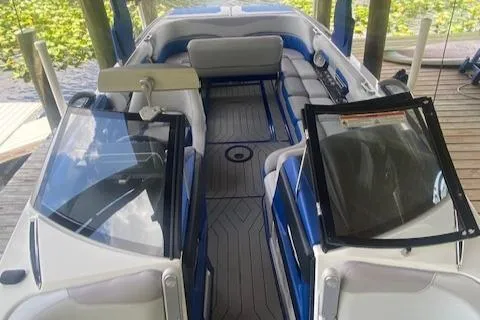 Slide: The Image of 2016 Malibu Wakesetter 25 LSV boat interior with blue and white seating under a dock. - 15