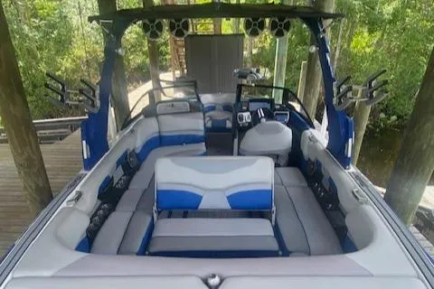 Slide: The Image of 2016 Malibu Wakesetter 25 LSV interior with blue and gray seating, docked in a wooded area. - 16