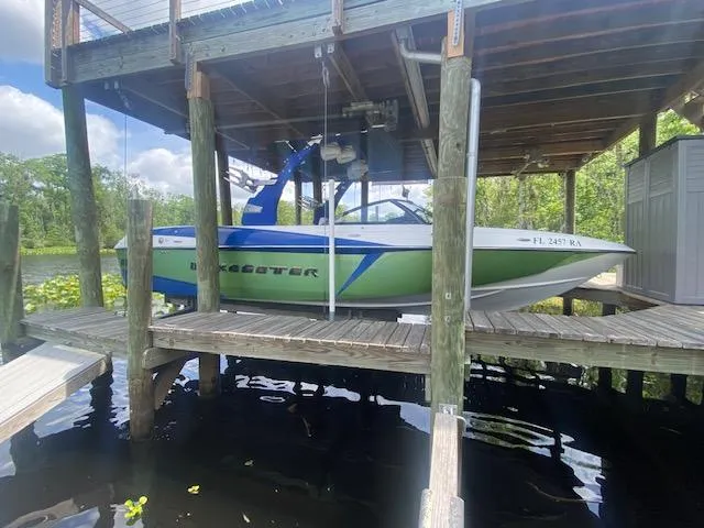Slide: The Image of 2016 Malibu Wakesetter 25 LSV boat docked under a wooden shelter. - 26