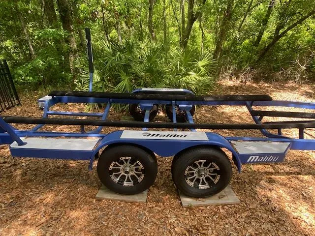 Slide: The Image of Blue trailer for 2016 Malibu Wakesetter 25 LSV, parked in wooded area. - 30