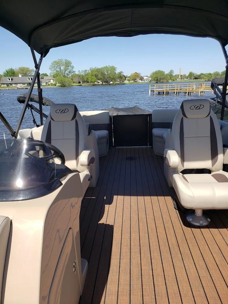 Slide: The Image of 2025 Bentley Pontoons Legacy Navigator on a serene lake, featuring spacious seating and elegant design. - 2