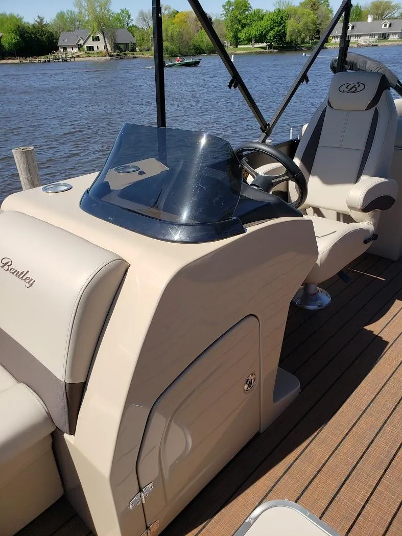 Slide: The Image of 2025 Bentley Pontoons Legacy Navigator on a serene lake, showcasing luxurious seating and helm. - 6