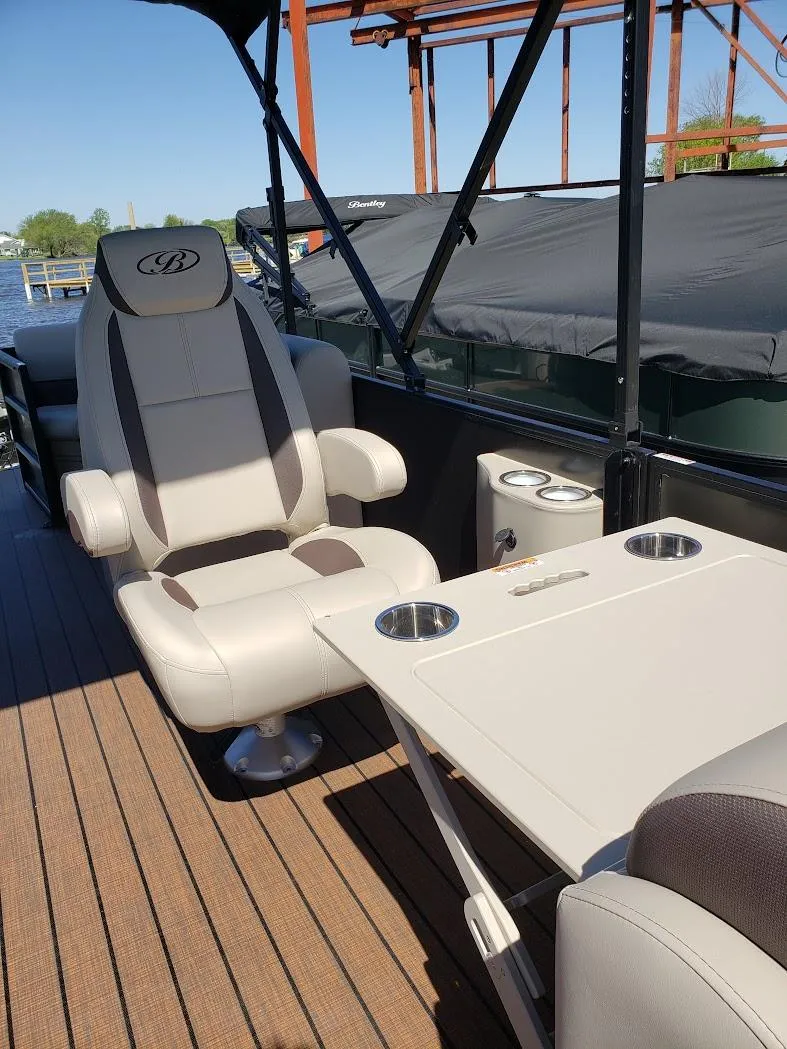 Slide: The Image of 2025 Bentley Pontoons Legacy Navigator interior with luxury seating and table on a sunny day. - 7