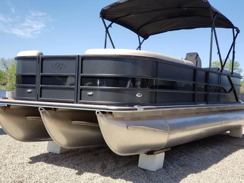 Slide: The Image of 2025 Bentley Pontoons Legacy Navigator on gravel, featuring sleek design and canopy. - 8