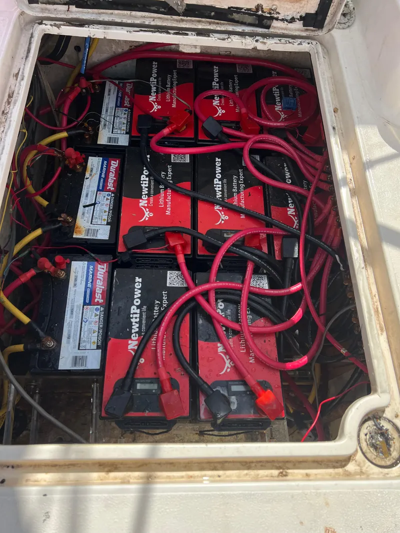 Slide: The Image of Battery compartment of a 1996 Prout 45 boat, featuring multiple red batteries and wiring. - 25