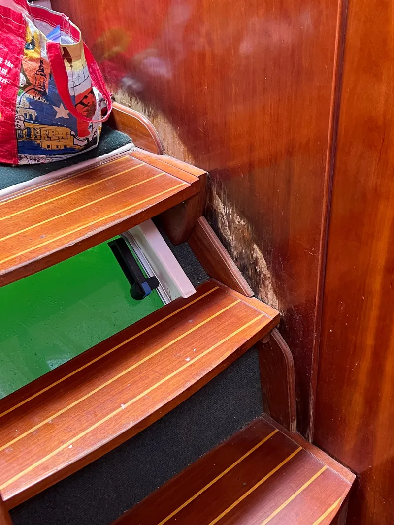 Slide: The Image of Wooden stairs inside a 1996 Prout 45 boat, with a colorful bag on top. - 43