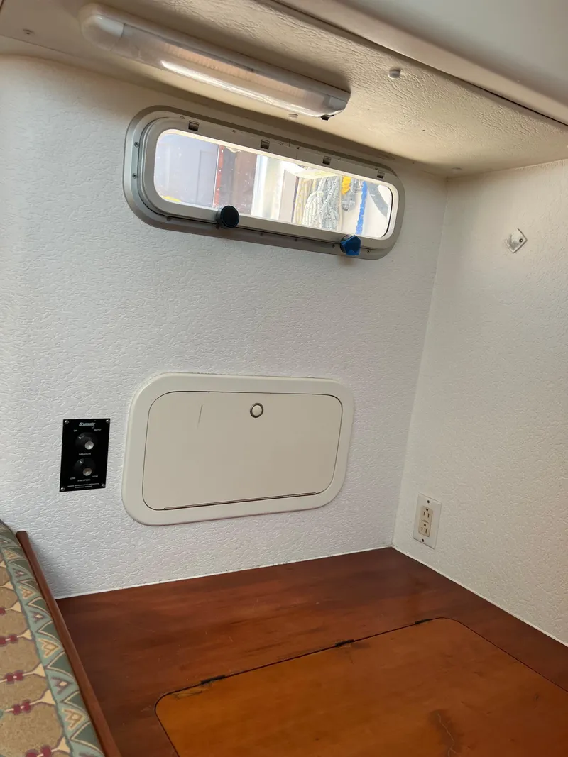 Slide: The Image of Interior cabin of a 1996 Prout 45 boat, featuring a small window and wooden surface. - 48