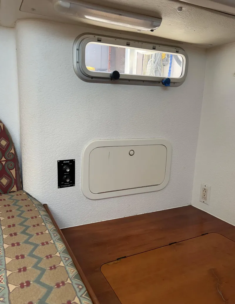 Slide: The Image of Interior of a 1996 Prout 45 boat, featuring a small window and wooden surfaces. - 49