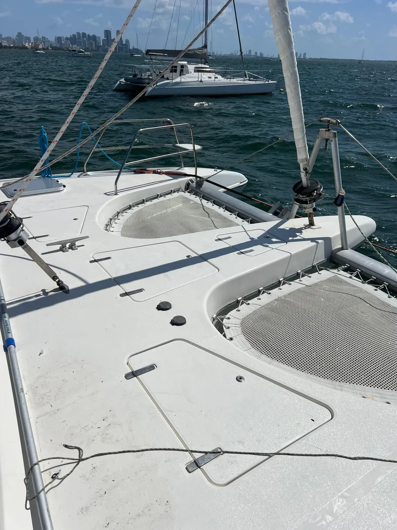 Slide: The Image of 1996 Prout 45 catamaran on water, featuring spacious deck and netting, with city skyline in background. - 5