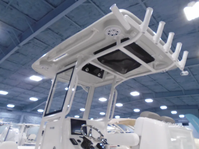Slide: The Image of 2025 Caymas 24 HB boat with T-top and rod holders in showroom. - 11