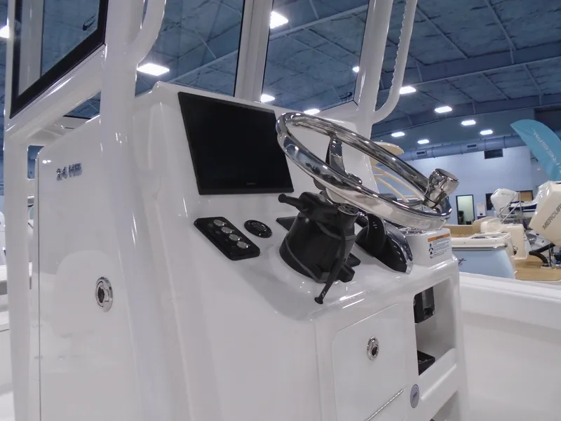 Slide: The Image of 2025 Caymas 24 HB boat console with steering wheel and controls in a showroom. - 12