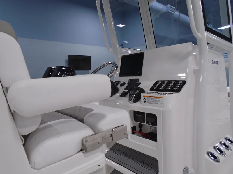 Slide: The Image of 2025 Caymas 24 HB boat interior with modern dashboard and white seating. - 8