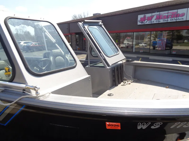 Slide: The Image of 2017 Crestliner CCM185 boat with open windshield, parked near a storefront. - 12