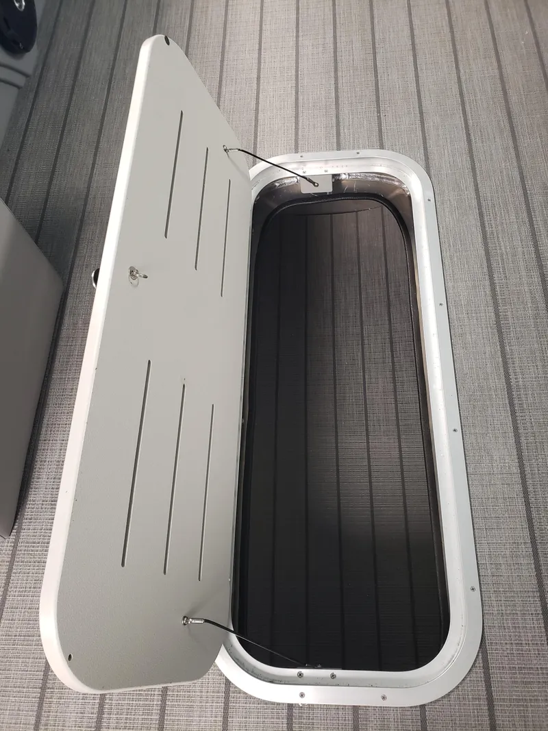 Slide: The Image of 2025 Bentley Pontoons Legacy Navigator storage compartment with open lid on textured flooring. - 9