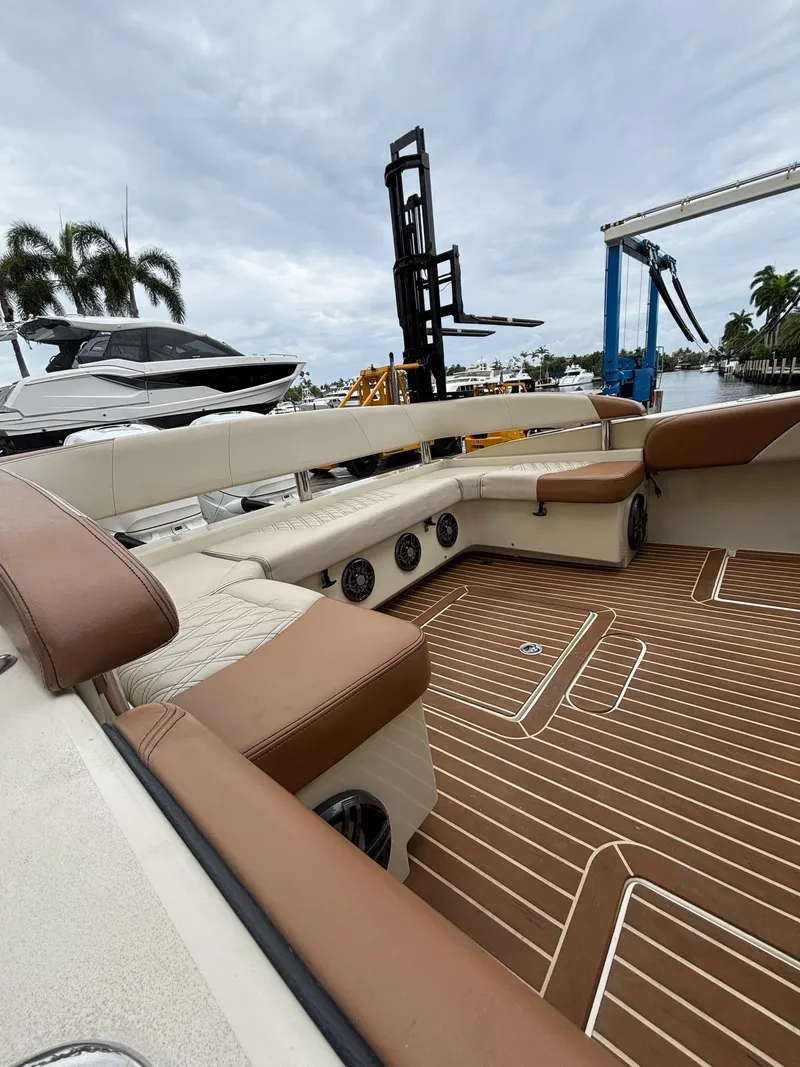Slide: The Image of 2013 Statement 35 Center Console boat interior with brown and beige seating, docked near palm trees. - 32