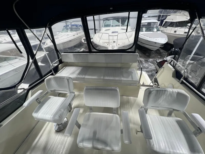 Slide: The Image of 1987 Tollycraft 30 Sport Cruiser interior with white seating and surrounding boats. - 10