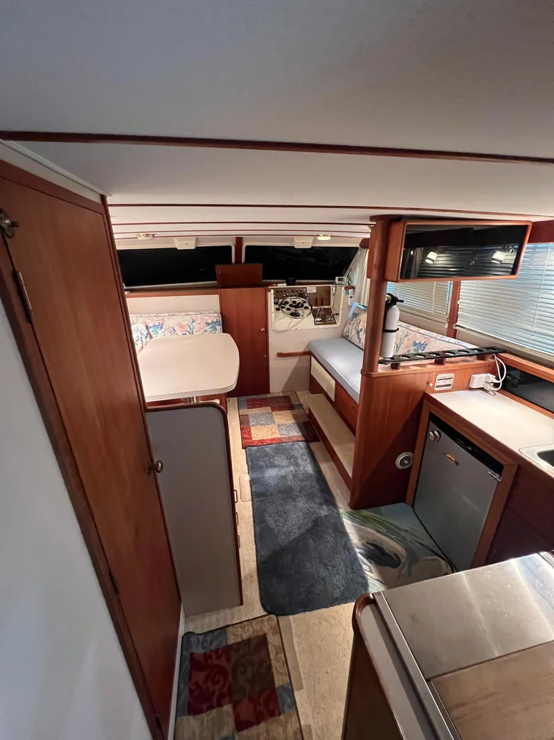 Slide: The Image of 1987 Tollycraft 30 Sport Cruiser interior with cozy seating, kitchenette, and wood accents. - 12