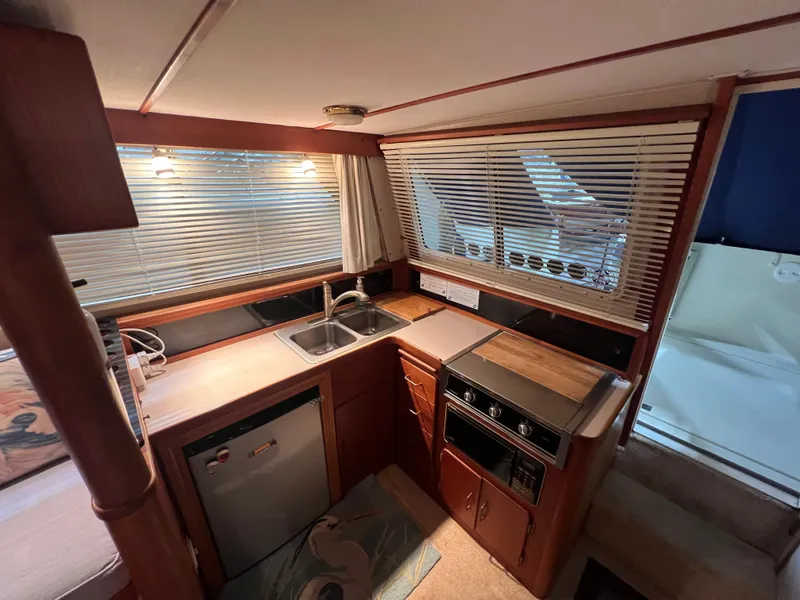 Slide: The Image of 1987 Tollycraft 30 Sport Cruiser kitchen with wood cabinetry, sink, and appliances. - 13