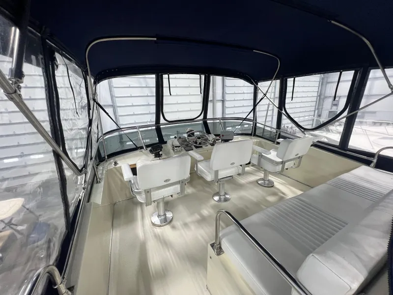 Slide: The Image of 1987 Tollycraft 30 Sport Cruiser interior with helm, seating, and enclosed canopy. - 7