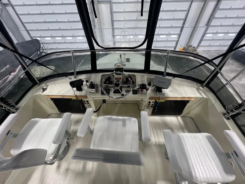 Slide: The Image of 1987 Tollycraft 30 Sport Cruiser helm with steering wheel and seating in a covered dock. - 8