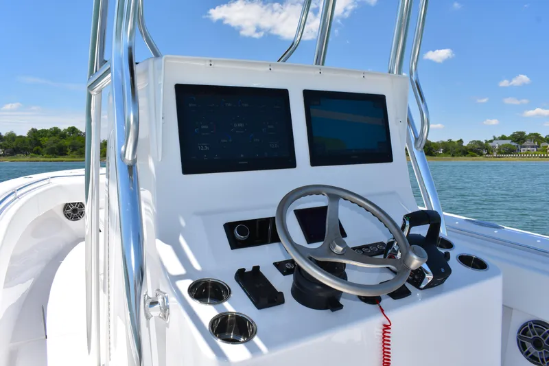 Slide: The Image of 2024 Contender 28 Tournament boat dashboard with dual screens and steering wheel, on a sunny day. - 18