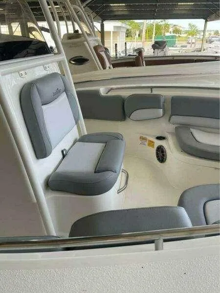 Slide: The Image of 2022 NauticStar 2102 Legacy boat interior with gray seating under a covered dock. - 16