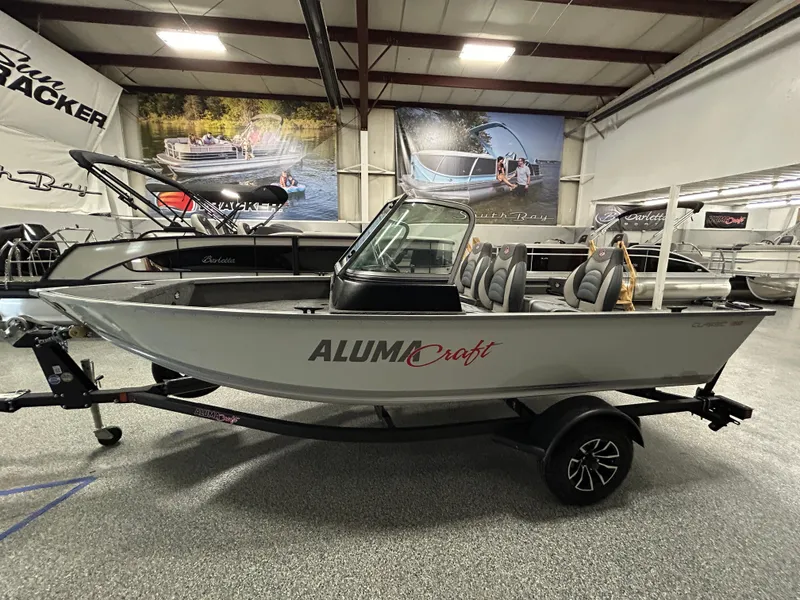 Slide: The Image of 2024 Alumacraft Classic 165 Sport boat displayed in showroom, side view. - 3