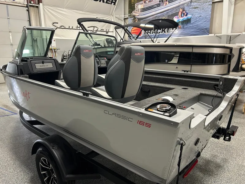 Slide: The Image of 2024 Alumacraft Classic 165 Sport boat in showroom, featuring sleek design and modern seating. - 4