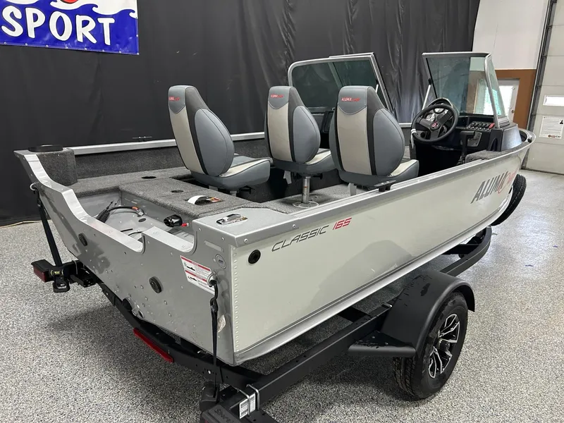 Slide: The Image of 2024 Alumacraft Classic 165 Sport boat with seating, displayed indoors on a trailer. - 6