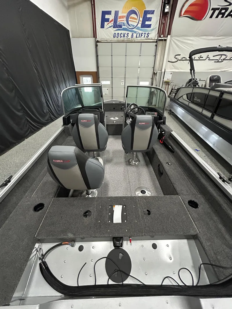 Slide: The Image of 2024 Alumacraft Classic 165 Sport boat interior with seating and dashboard in showroom. - 7