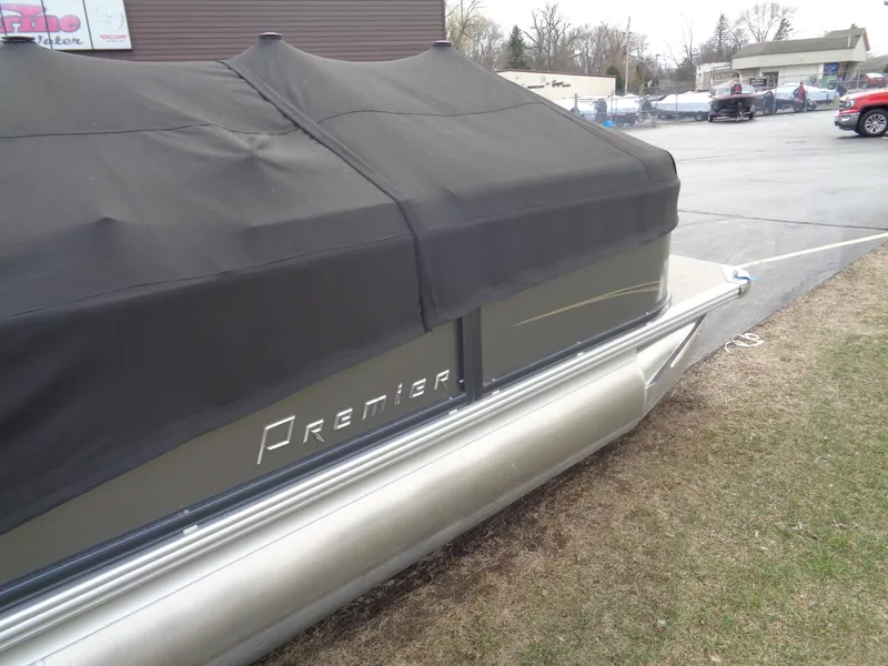 Slide: The Image of 2022 Premier 210 Sunspree pontoon boat with black cover, parked on grass. - 24