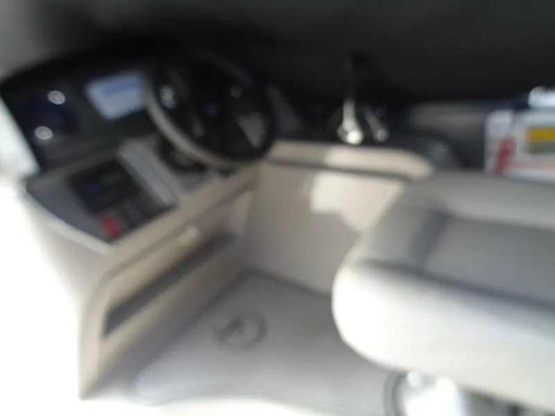 Slide: The Image of Blurry interior of 2022 Premier 210 Sunspree boat, featuring steering wheel and seating area. - 31