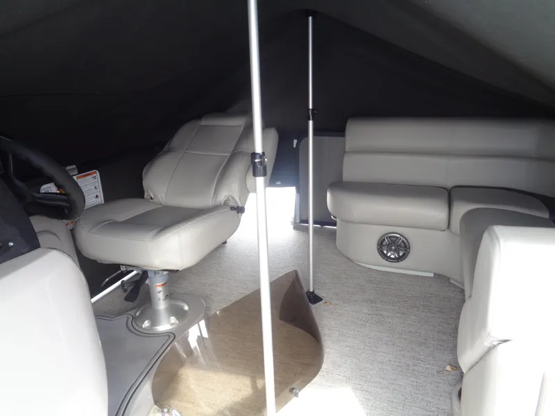 Slide: The Image of 2022 Premier 210 Sunspree boat interior with beige and gray seating, cup holder, and speaker. - 9
