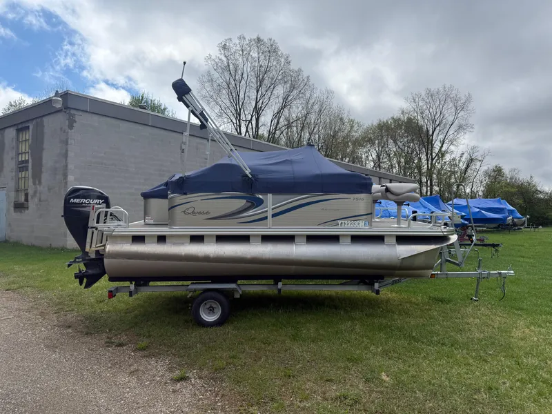 Slide: The Image of 2016 Apex Marine Qwest Adventure 7516 pontoon boat on trailer, parked on grass. - 1