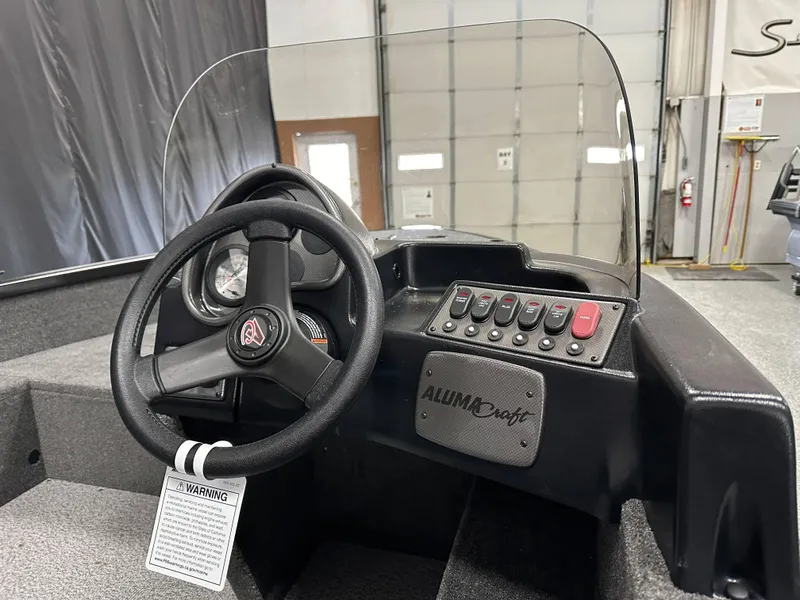 Slide: The Image of 2024 Alumacraft Classic 165 SC boat dashboard with steering wheel and control panel. - 14