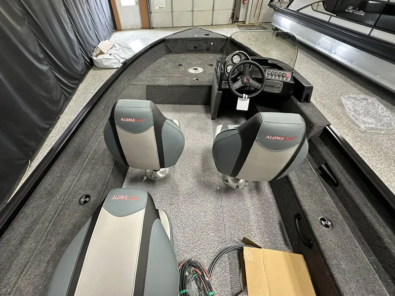 Slide: The Image of 2024 Alumacraft Classic 165 SC boat rear view in showroom setting. - 23
