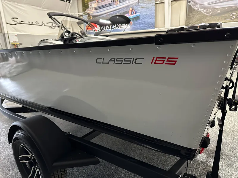 Slide: The Image of 2024 Alumacraft Classic 165 SC boat interior with carpeted deck and storage compartments. - 4