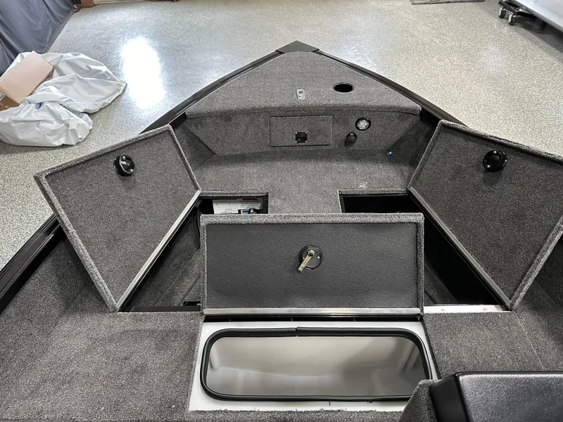 Slide: The Image of 2024 Alumacraft Classic 165 SC fishing boat interior in showroom, featuring seating and storage. - 7