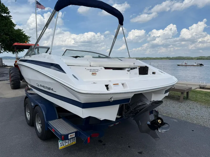 Slide: The Image of 2012 Regal 2000 Bowrider boat on trailer by a lake, under a cloudy sky. - 3