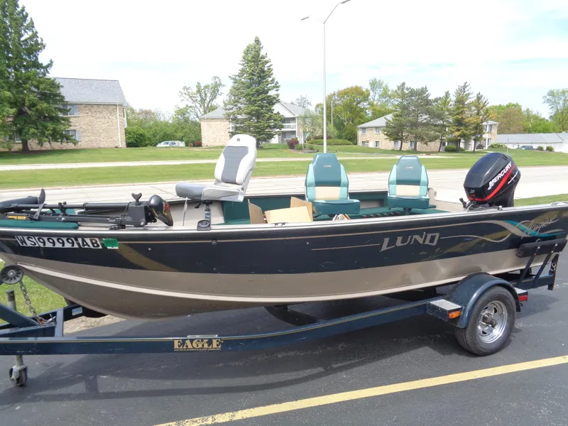 Slide: The Image of 1999 Lund 1650 Angler boat on trailer, parked outdoors, with three seats and an outboard motor. - 14