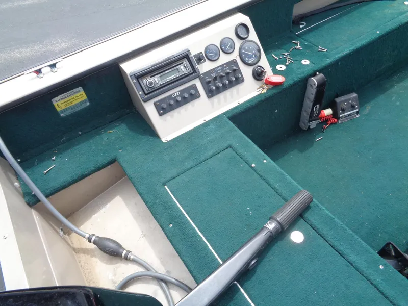 Slide: The Image of 1999 Lund 1650 Angler boat dashboard with green carpet and control panel. - 9
