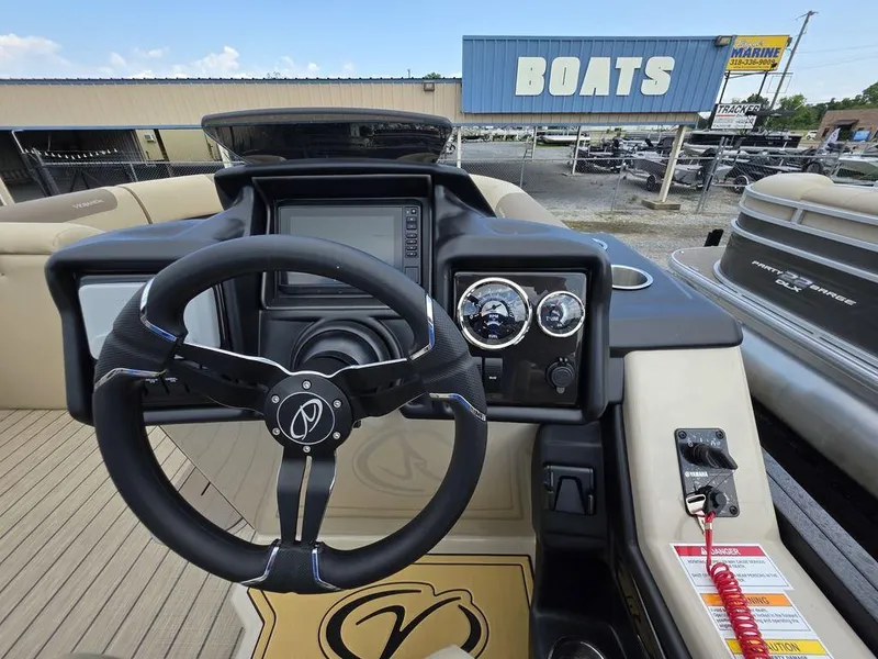 Slide: The Image of 2025 Veranda VR22RC XL Tri-Toon dashboard with steering wheel and control panel at a boat dealership. - 24