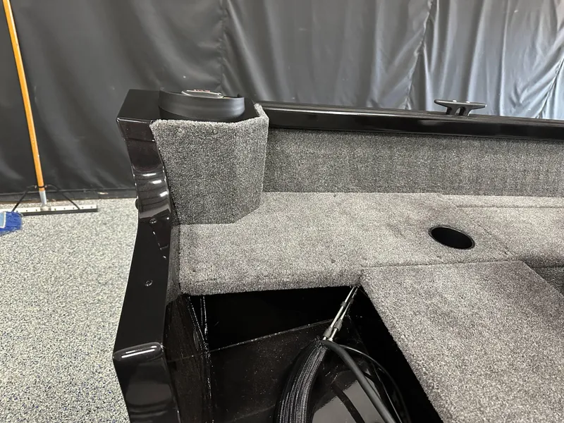 Slide: The Image of 2024 Alumacraft Classic 165 SC boat interior with gray carpet and storage compartment. - 15