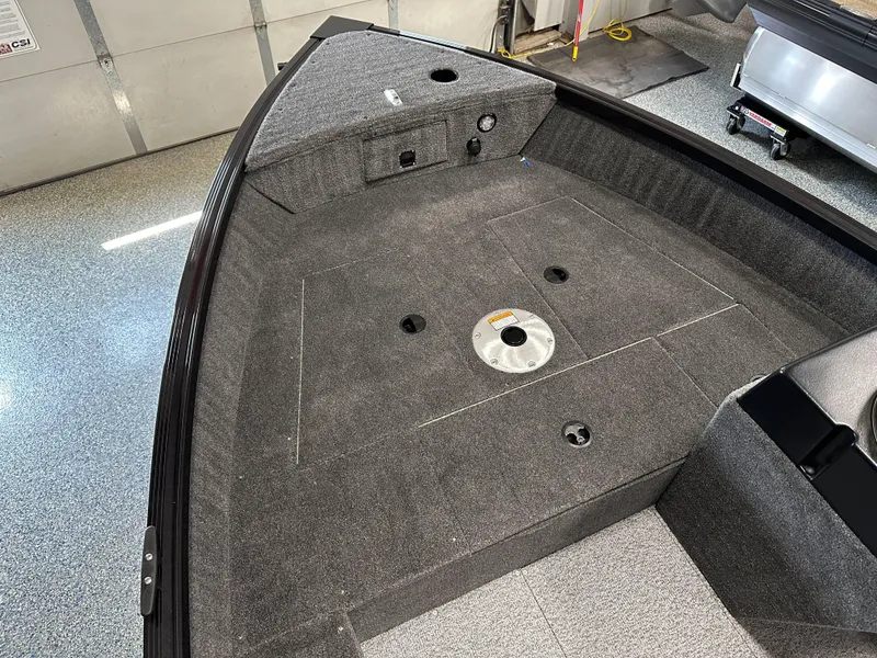 Slide: The Image of 2024 Alumacraft Classic 165 SC boat interior with carpeted deck in a garage setting. - 5